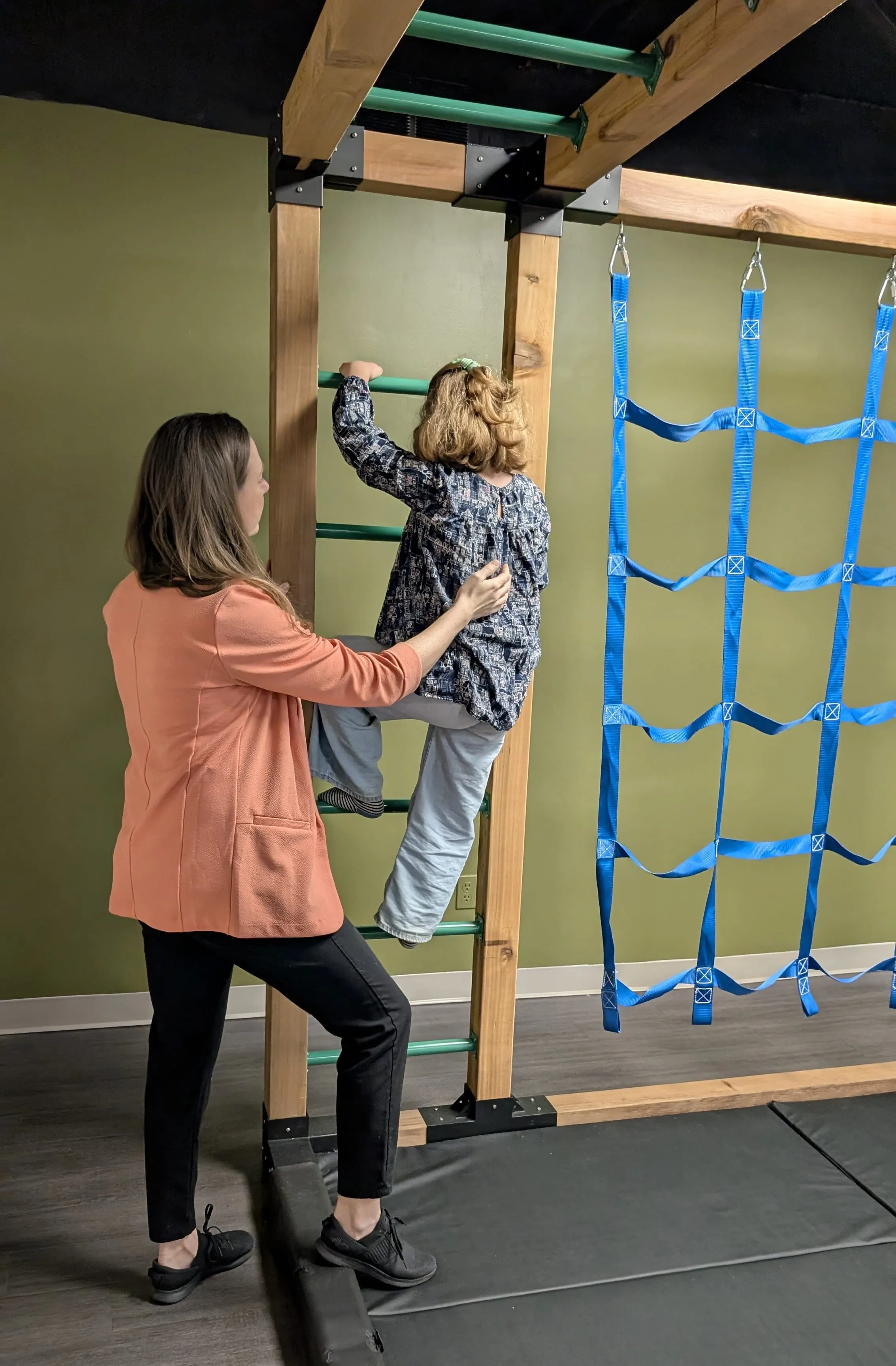 A child climbing in Together OT's therapy space